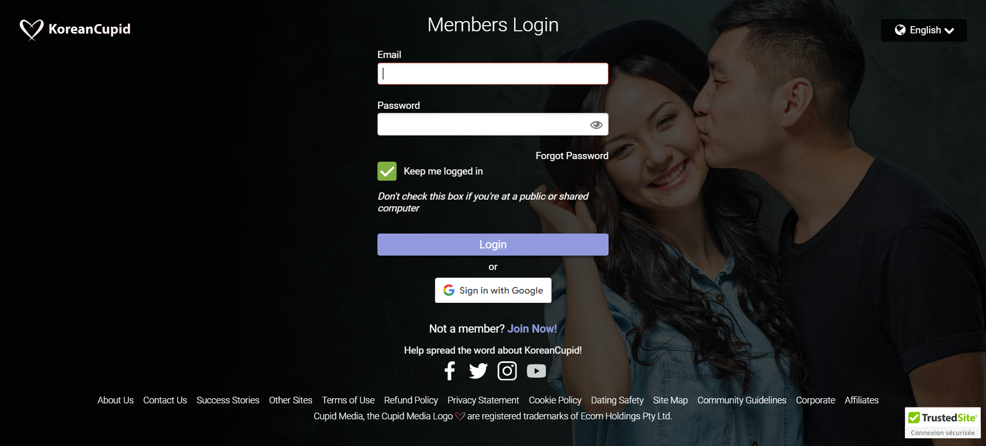 A couple shares a kiss in front of a login screen, capturing a moment of affection amidst technology.
